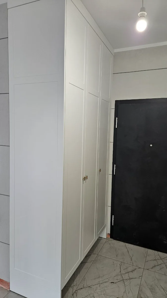 Biała szafa na wymiar z frezowanymi frontami — korytarz